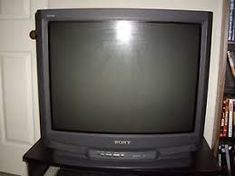 an old television sitting on top of a wooden table in front of a book shelf