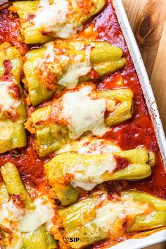 a casserole dish with zucchini, cheese and sauce in it on a wooden table