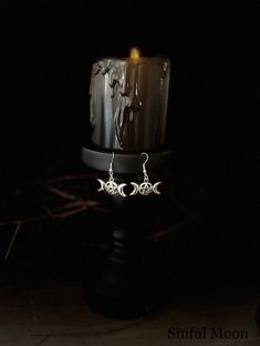 a candle is lit in the dark with earrings on it