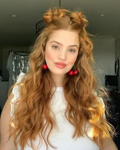 a woman with long red curly hair and earrings on her head looking at the camera