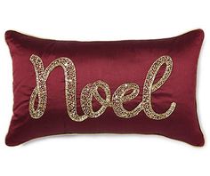 a red and gold pillow with the word noel spelled in sequins on it