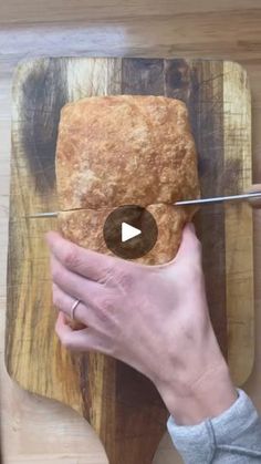 a person is cutting bread on a wooden board