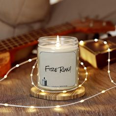 a lit candle sitting on top of a wooden table next to a guitar and string lights