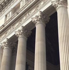 an old building with columns and clocks on the front