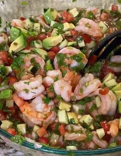 shrimp, avocado and tomato salad in a glass bowl with a black spoon