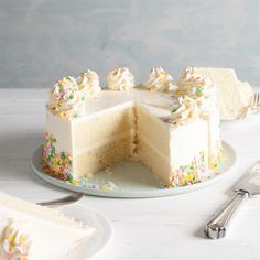 a cake with white frosting and sprinkles is cut in half on a plate