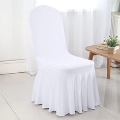 a white chair covered with a table cloth next to a small potted plant on a wooden table