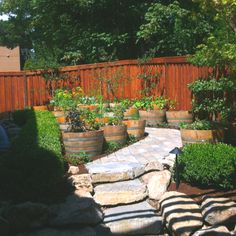 an outdoor garden with rocks and plants in the foreground, surrounded by wooden fence