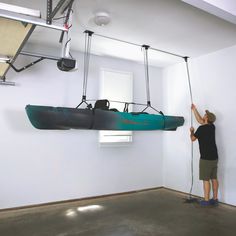 a man standing in front of a kayak suspended from the ceiling by two ropes