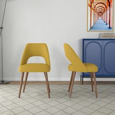 two yellow chairs sitting next to each other in front of a painting on the wall