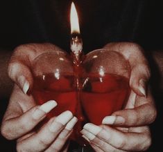 a person holding a heart shaped object with a candle in it's middle and hands