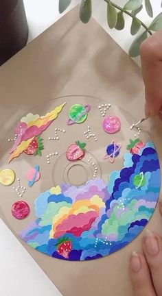 someone is painting a cd cover with buttons and other things on the disc as if it were made out of paper