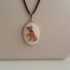 a small cross stitch dog in a round pendant