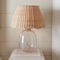 a glass lamp sitting on top of a white table next to a wall mounted clock