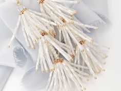 "NEW & WE ARE IN LOVE with these chic hand-beaded tassel wedding earrings, perfect for the boho bride at heart and a fun accessory to wear after the wedding too! Each piece is made in the USA. DETAILS *As shown, earrings feature soft white hand beaded tassels *The earrings measure about 4\" top to bottom and about 1\" wide *Finish is available in gold as shown The goal of your earrings is to compliment your dress and your overall wedding day look, not overpower it. We want our earrings to ma Elegant Beaded Earrings With Dangling Beads For Festive Occasions, Gold Tassel Earrings For Wedding, Festive White Crystal Earrings, White Dangle Tassel Earrings For Party, Wedding Jewelry With Tassels, Dangle Shape, Elegant Beaded Chandelier Earrings For Festive Occasions, White Tassel Earrings For Party, Silver Tassel Wedding Earrings, Festive White Dangle Crystal Earrings