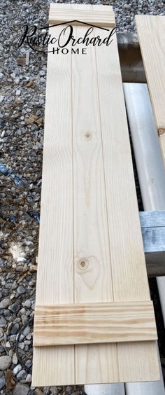 a wooden bench sitting on top of a gravel covered ground next to a metal rail