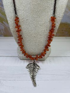 This is a Carnelian necklace with pear shaped rounded beads. The fern leaf pendant is silver plated, but the rose shaped beads are fine silver from Thailand. The brown beads are rounded and are regular beads.  This necklace is longer and sits at the bust line.  The necklace is 22 inches with the leaf extending that another 2 inches.  The clasp is a toggle, and silver plated. Carnelian Necklace, Fern Leaf, Reno Nv, Blue Topaz Pendant, Carnelian Beads, The Leaf, Leaf Pendant, London Blue Topaz, The Rose