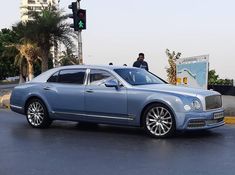 a blue car parked on the side of a road next to a traffic light with a man standing behind it