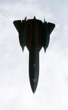 a fighter jet flying through the sky with red markings