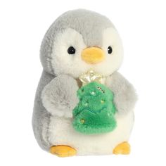 a stuffed penguin holding a small christmas tree