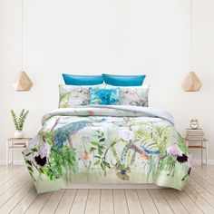 a bed covered in a green and blue comforter next to a plant filled wall