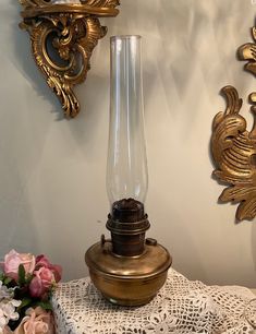 an old fashioned lamp sitting on top of a doily next to some wall sconces