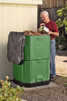 a man standing next to a green trash can