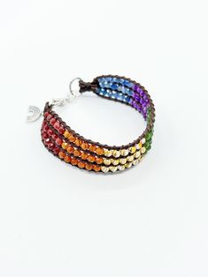 Share your pride and/or be an LGBTQ+ ally with this boho chic handwoven gemstone beaded cuff bracelet. Six sets of eighteen faceted round gemstones represent the colors of the Pride flag; rare red lazasine (red labradorite), orange hessonite garnet, yellow citrine, green jade, purple amethyst and blue kyanite. The stones are painstakingly hand woven between strips of brown leather cord. The cuff is finished with a sterling silver rainbow charm, sterling silver lobster clasp and links. The bracelet is .75 inches wide by 7.5 inches long.  Not just for the month of June....shout to the world that you believe in equality. Love is love. Please feel free to contact me with questions. I ship USPS Priority Mail and your bracelet will arrive in a box suitable for gift giving. Enjoy! Bohemian Rainbow Beaded Bracelets With Natural Stones, Bohemian Rainbow Beaded Bracelet With Gemstone Beads, Bohemian Rainbow Gemstone Beaded Bracelets, Bohemian Rainbow Friendship Bracelets Hand-strung, Bohemian Rainbow Hand-strung Friendship Bracelets, Adjustable Rainbow Crystal Bracelet With Gemstone Beads, Adjustable Rainbow Crystal Bohemian Bracelet, Hand-strung Bohemian Rainbow Jewelry, Adjustable Rainbow Beaded Crystal Bracelet