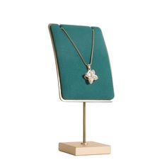 a necklace on a display stand with a green velvet pad and gold plated chain