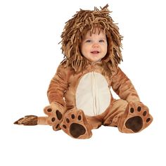 a baby sitting on the ground wearing a lion costume