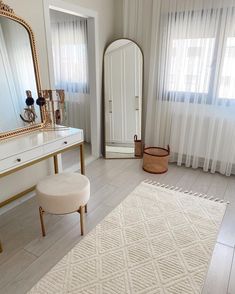 a white room with a mirror, vanity and stool