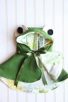 a green frog hat and bib on a white wall