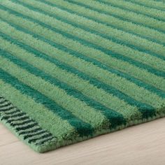 a green rug with vertical stripes on the top and bottom, sitting on a wooden floor