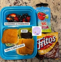 two plastic containers filled with food on top of a marble countertop next to a bag of chips