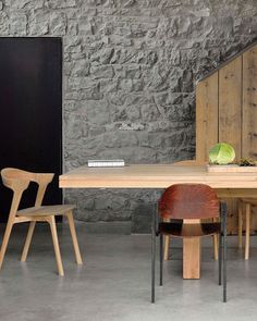 a wooden table with four chairs next to it and a stone wall in the background