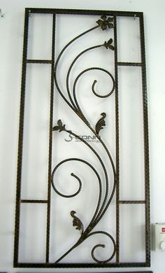 an iron window frame with vines and flowers on the bottom, hanging from a wall