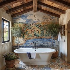 a bath tub sitting under a window next to a painting on the side of a wall