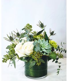 a vase filled with white flowers and greenery