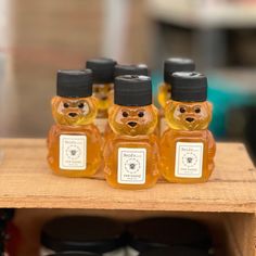 four honey bears with labels on them sitting on a wooden shelf in front of other jars