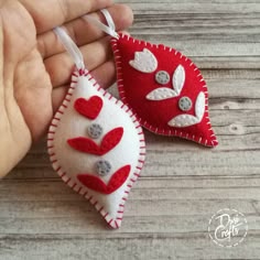 two red and white heart shaped ornaments hanging from strings on a wooden table with text overlay that says, felt hearts for valentine's day