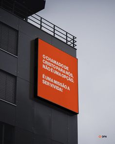 an orange sign hanging off the side of a building in front of a cloudy sky