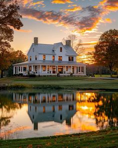 a large white house sitting on top of a lush green field next to a lake