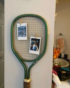 a tennis racket hanging on the wall with photos pinned to it's side