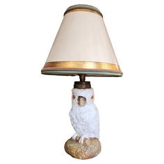 a white owl lamp sitting on top of a table next to a beige shade lampshade