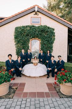 a group of people in suits and ties posing for a photo with a wedding dress