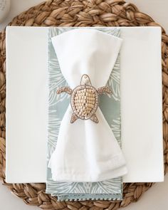 a place setting with napkins and sea turtle brooch