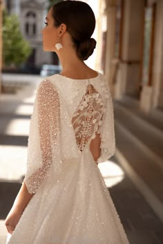 a woman in a white dress is standing on the street with her back to the camera