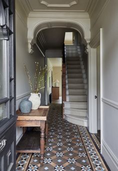 an entryway with stairs and tiled flooring in the hallway leading to another room