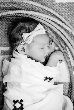 a black and white photo of a baby sleeping in a basket with a blanket on it