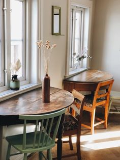 a wooden table sitting next to a window in a room with two chairs and a vase on top of it